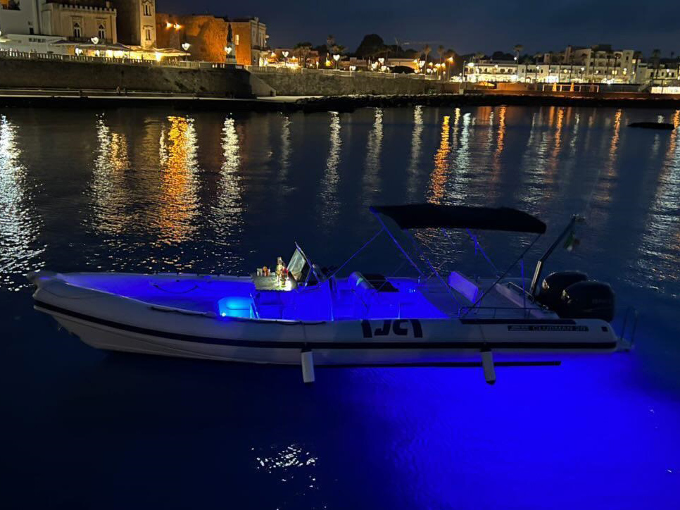 Una vista notturna della costa di Otranto con il gommone illuminato in primo piano